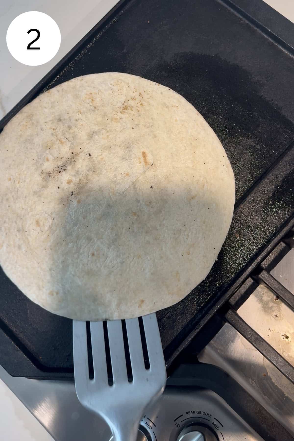 Flour tortilla on a cast iron griddle.