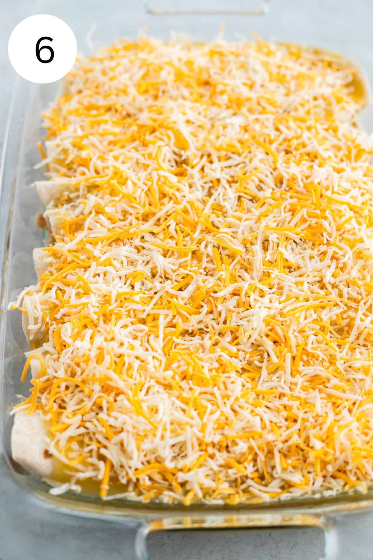 Enchiladas topped with shredded cheese.