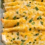 Chicken enchiladas topped with cilantro in a pan.