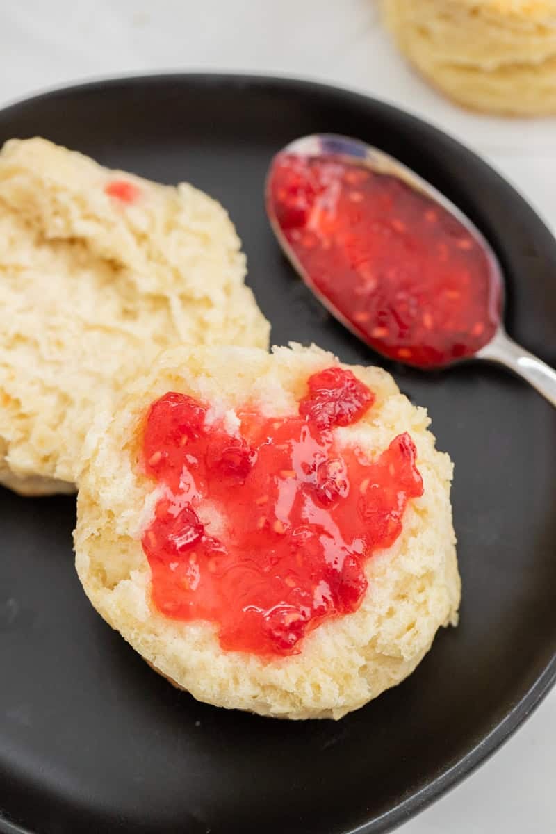 A biscuit cut in half with jam on one piece.