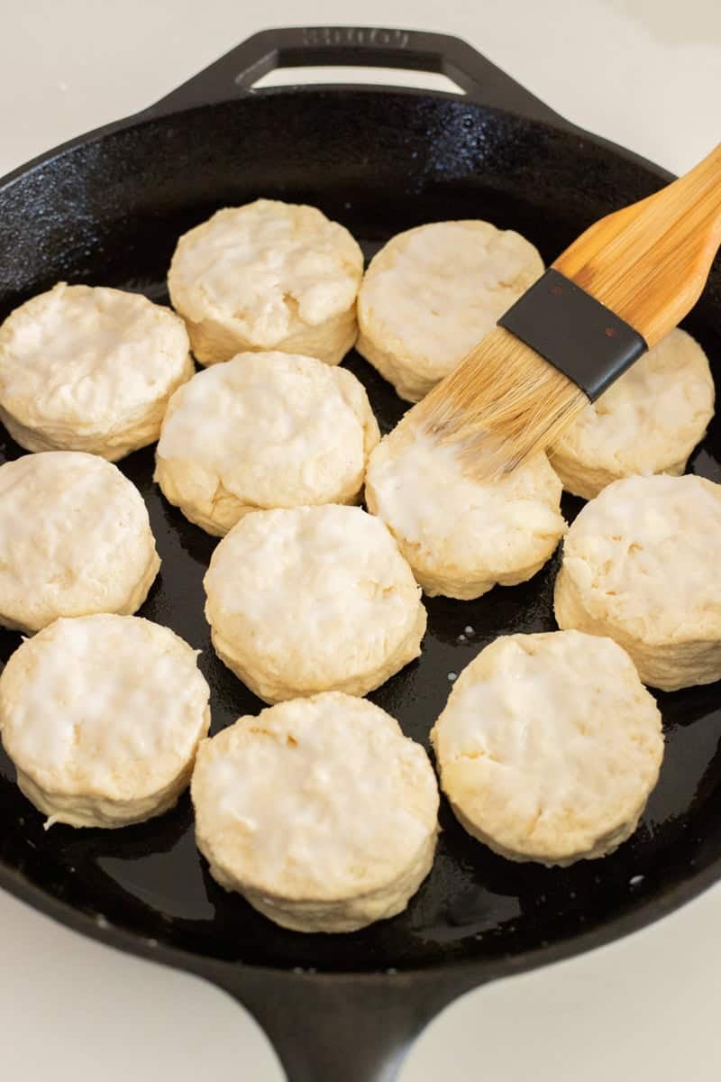 Biscuits brushed with buttermilk in cast iron pan.