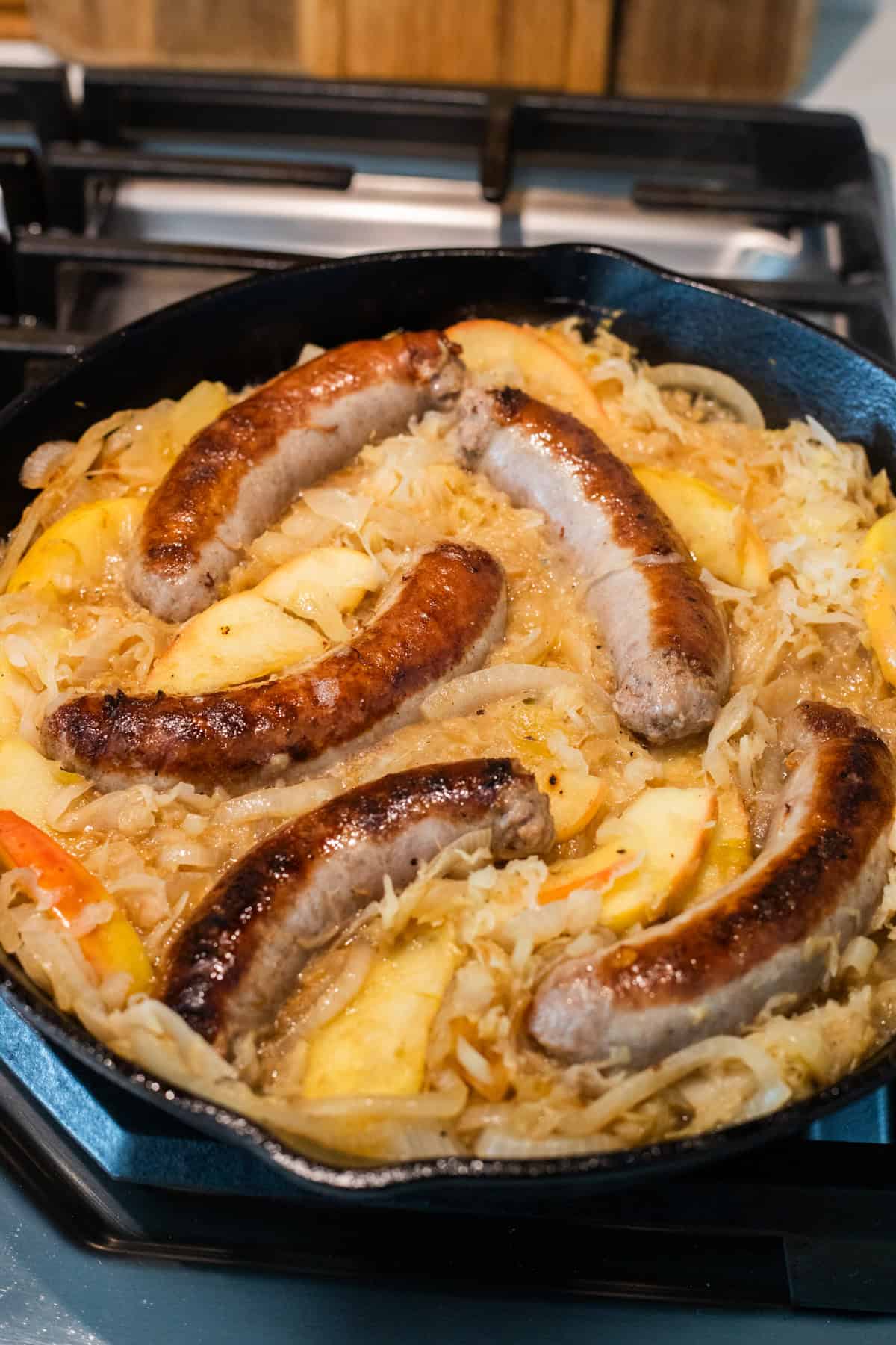 Brats simmering in sauerkraut in cast iron skillet.