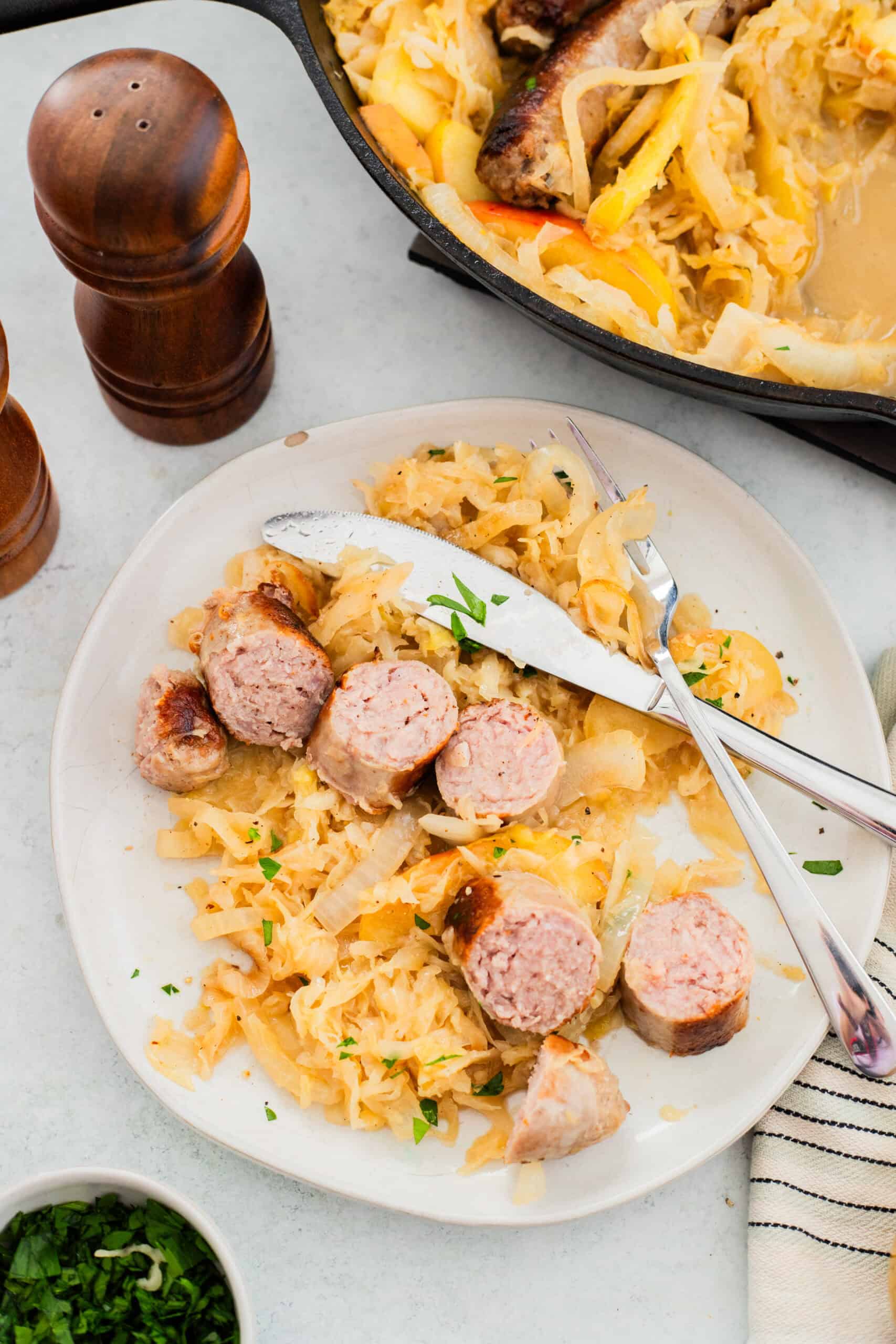A serving of bratwurst and sauerkraut on a white plate.