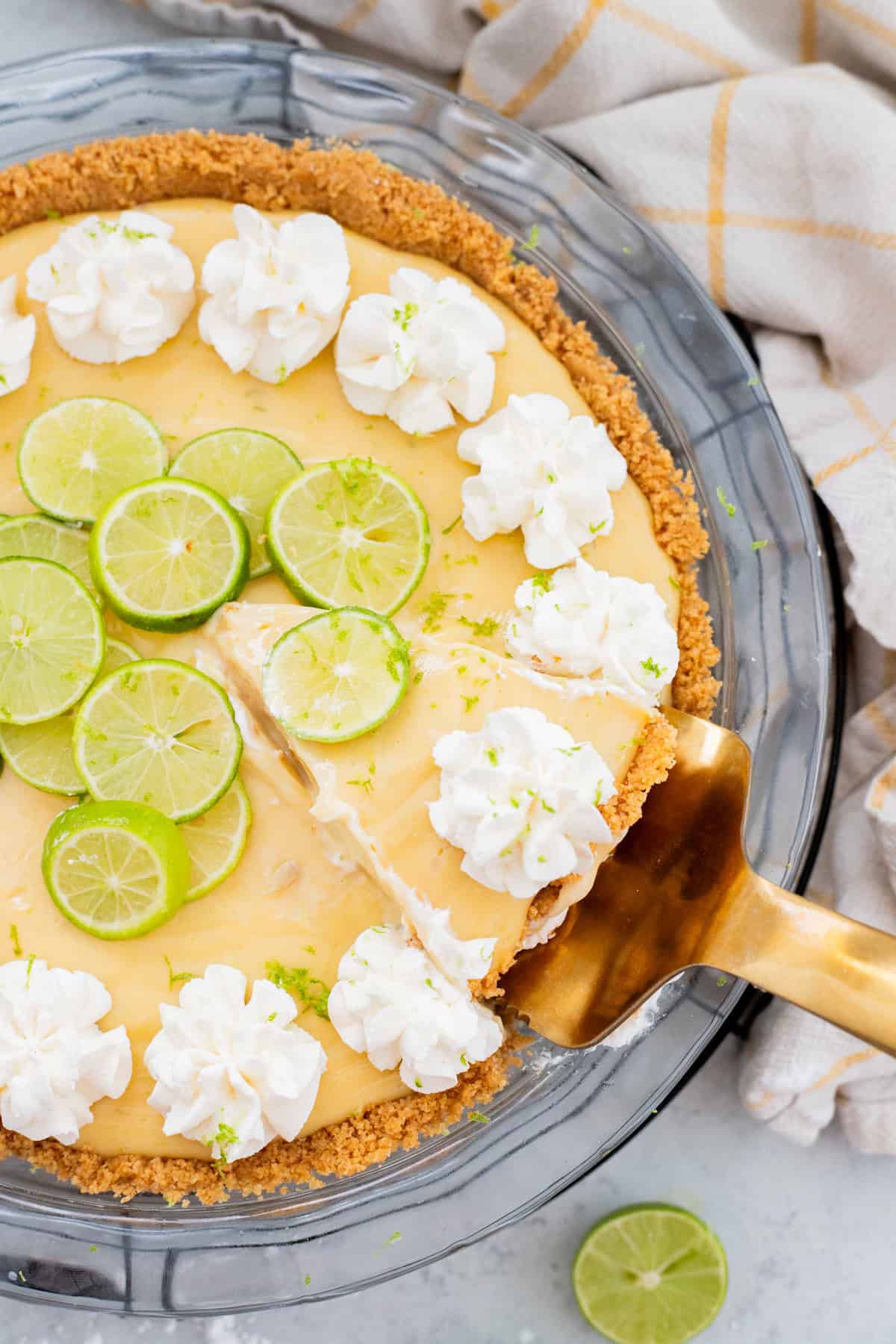 Gold pie server cutting into key lime pie.