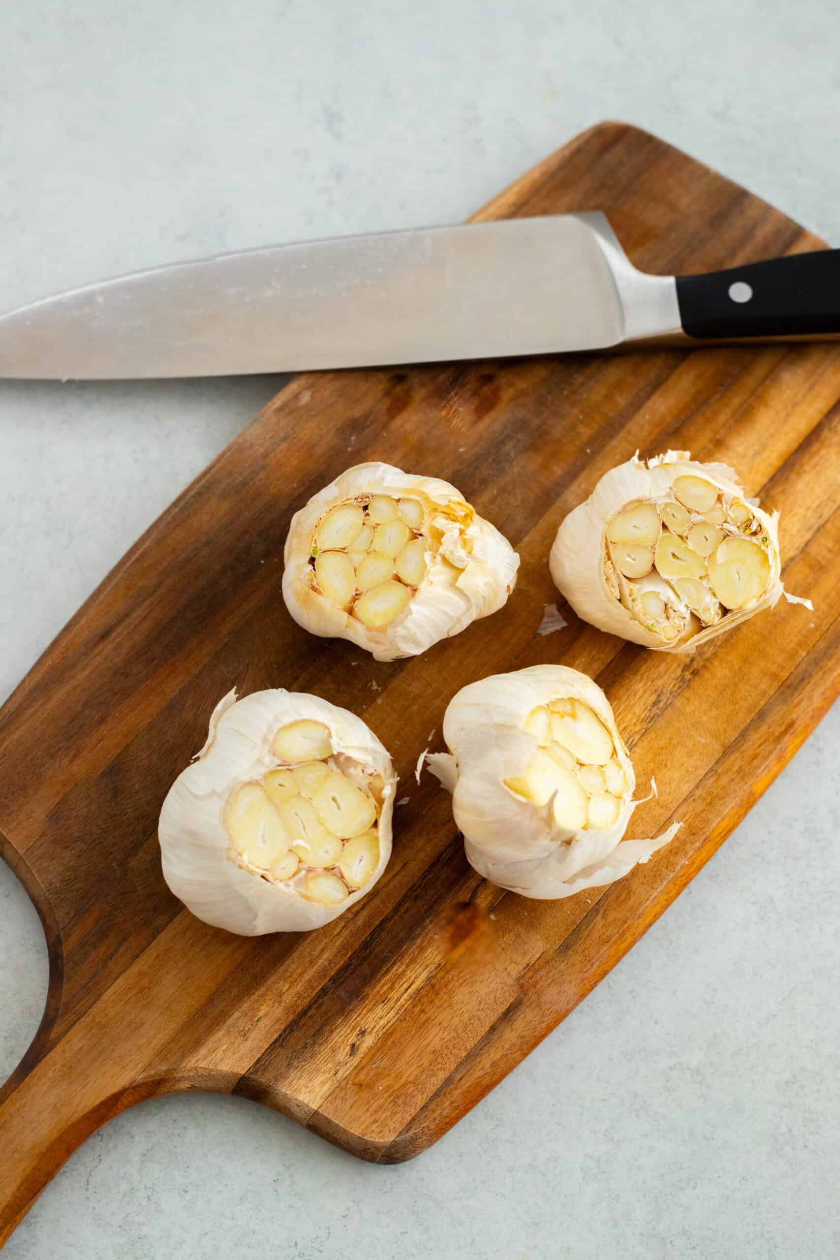 4 heads of garlic with the tops cut off to expose the cloves.