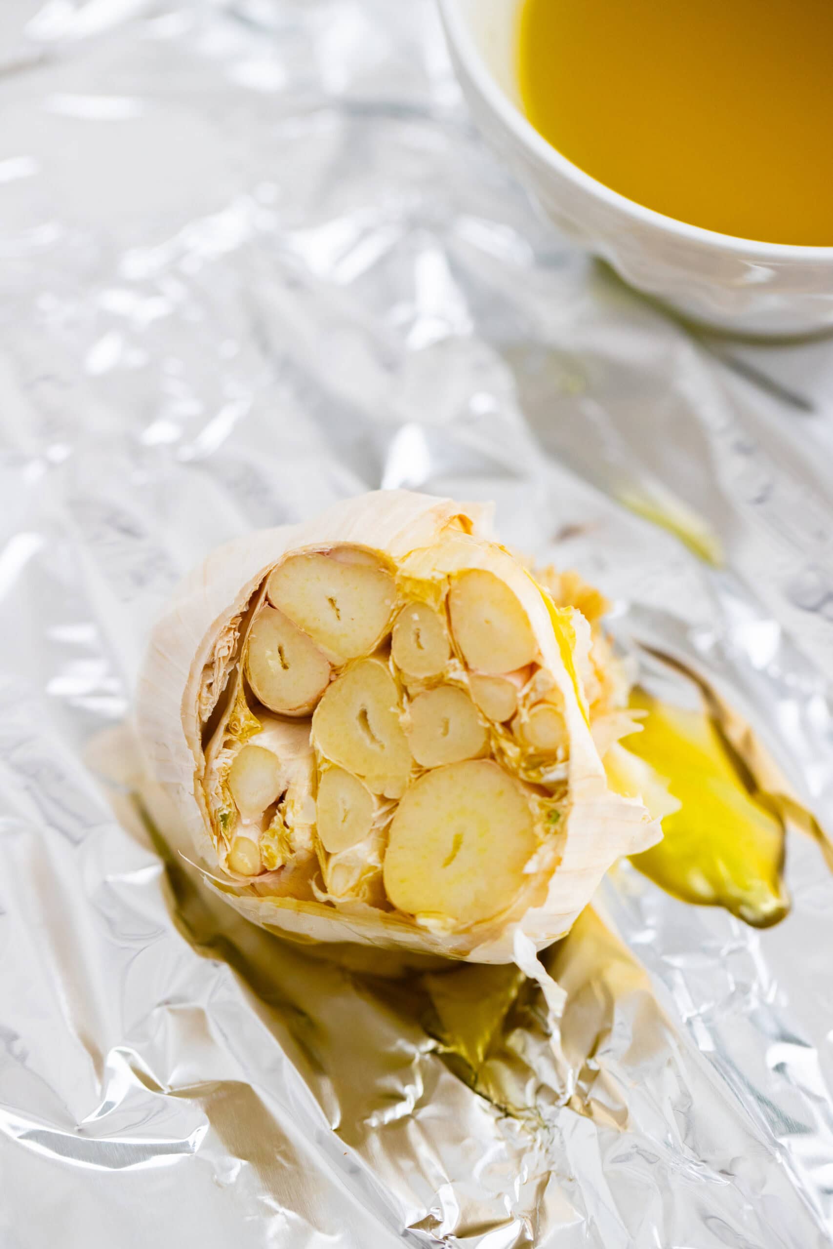 A head of garlic drizzled with olive oil and placed on a piece of foil.