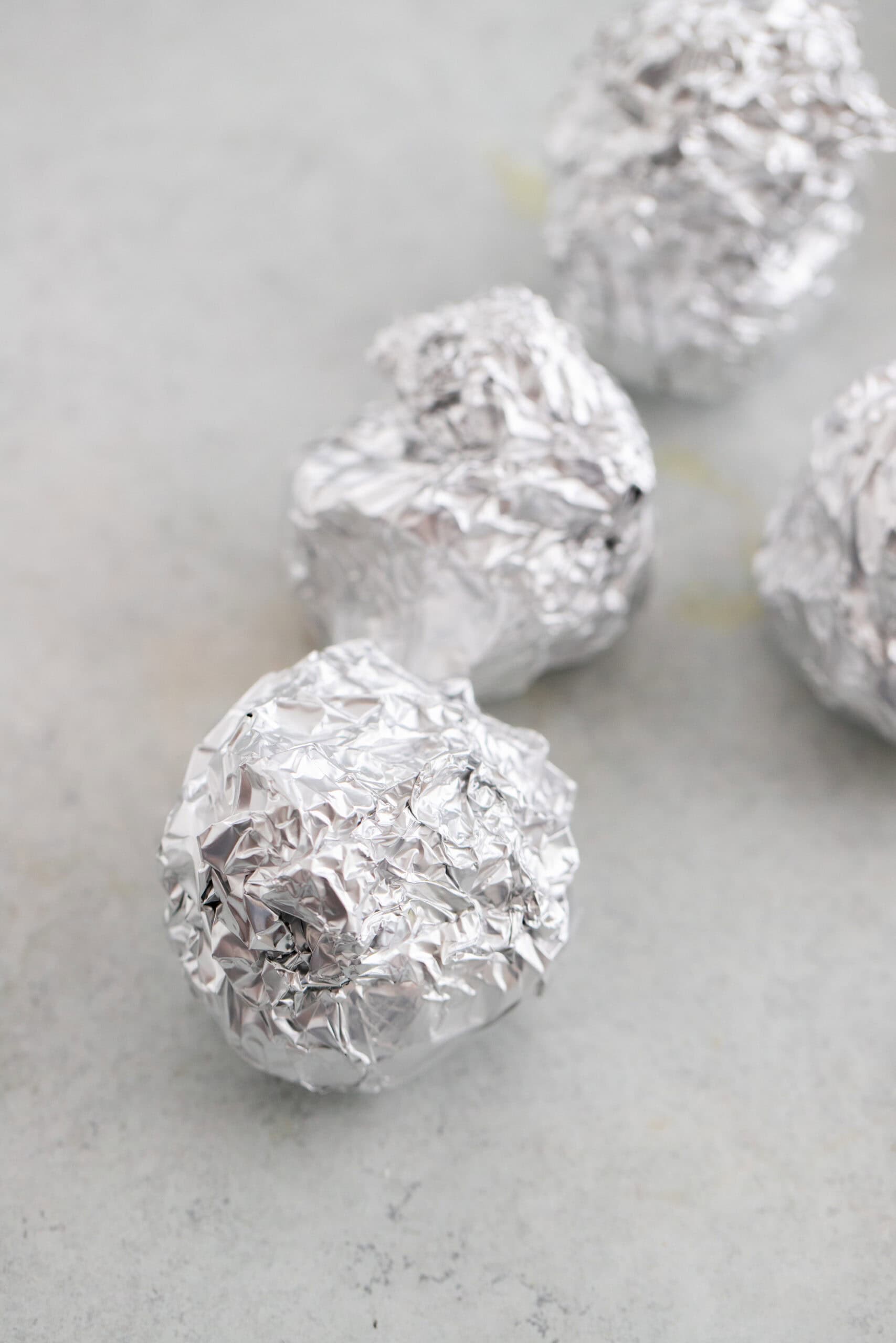 4 heads of garlic wrapped in aluminum foil.