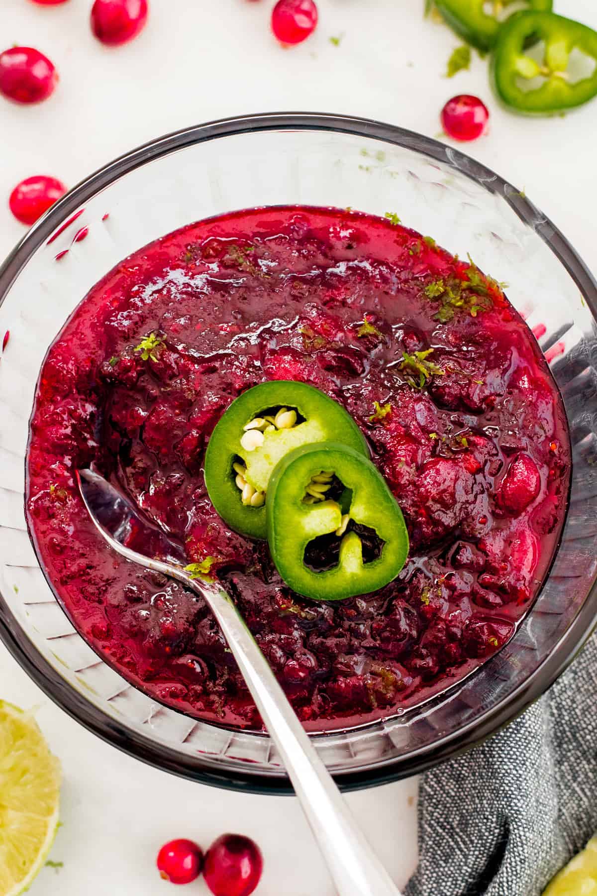 Jalapeno cranberry sauce garnished with jalapeno slices in a glass bowl.