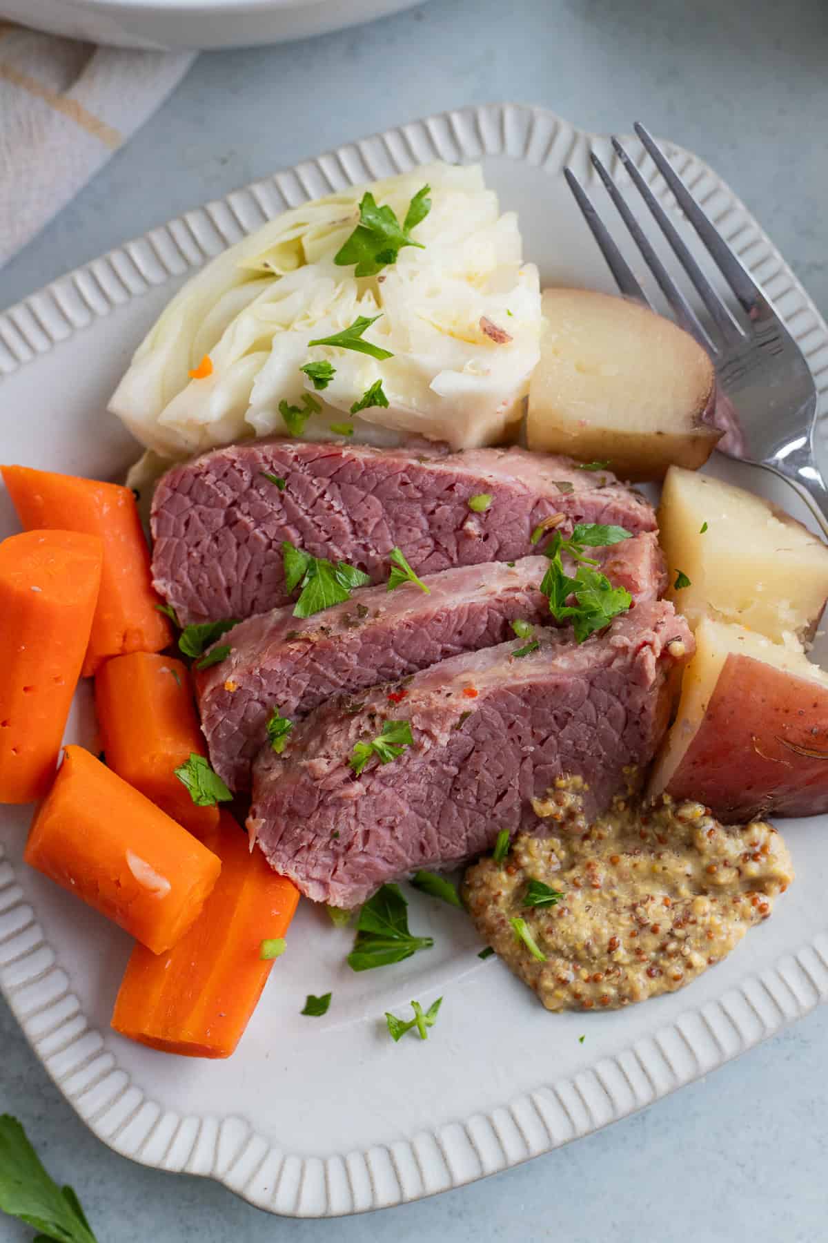 Sliced corned beef on a plate with veggies.