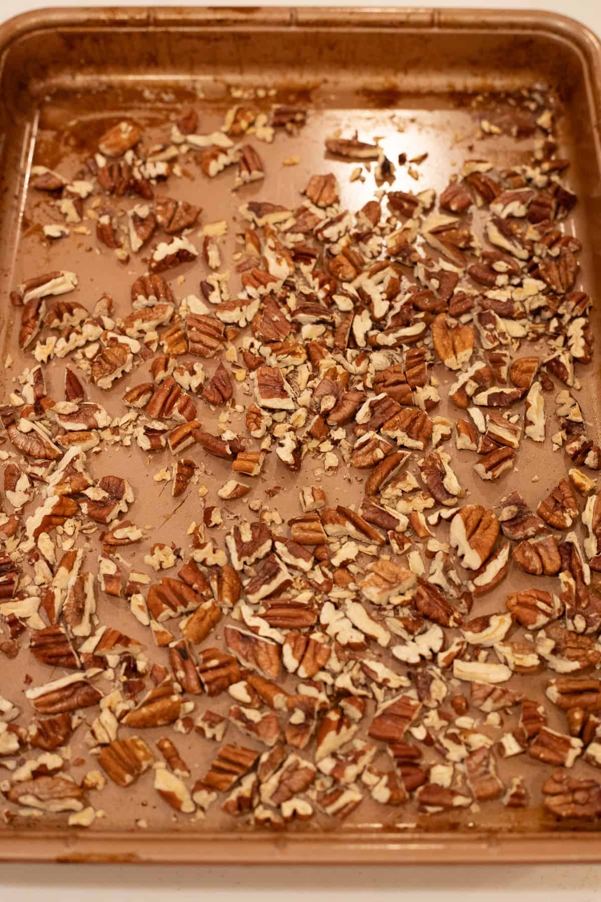 Chopped pecans on a baking sheet.