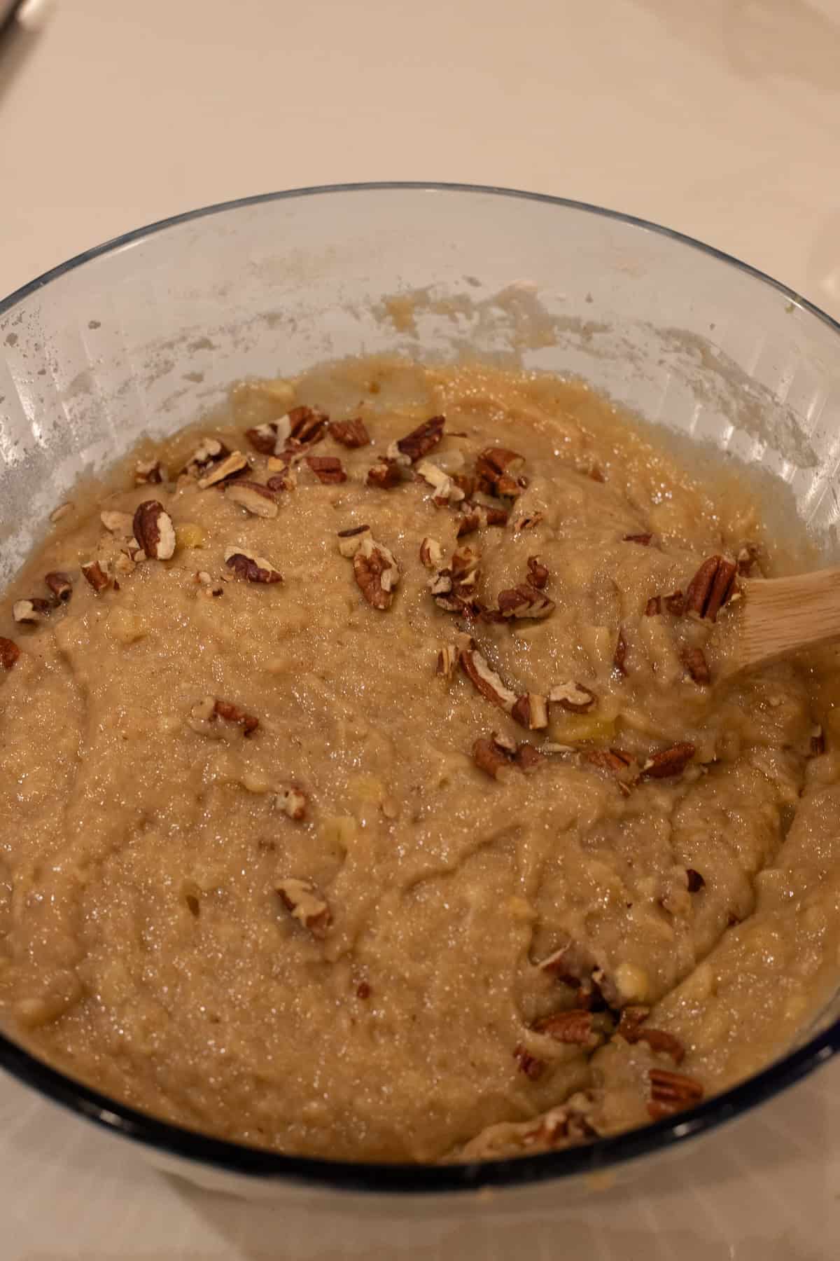 Hummingbird cake batter in a mixing bowl with pecans mixed in.