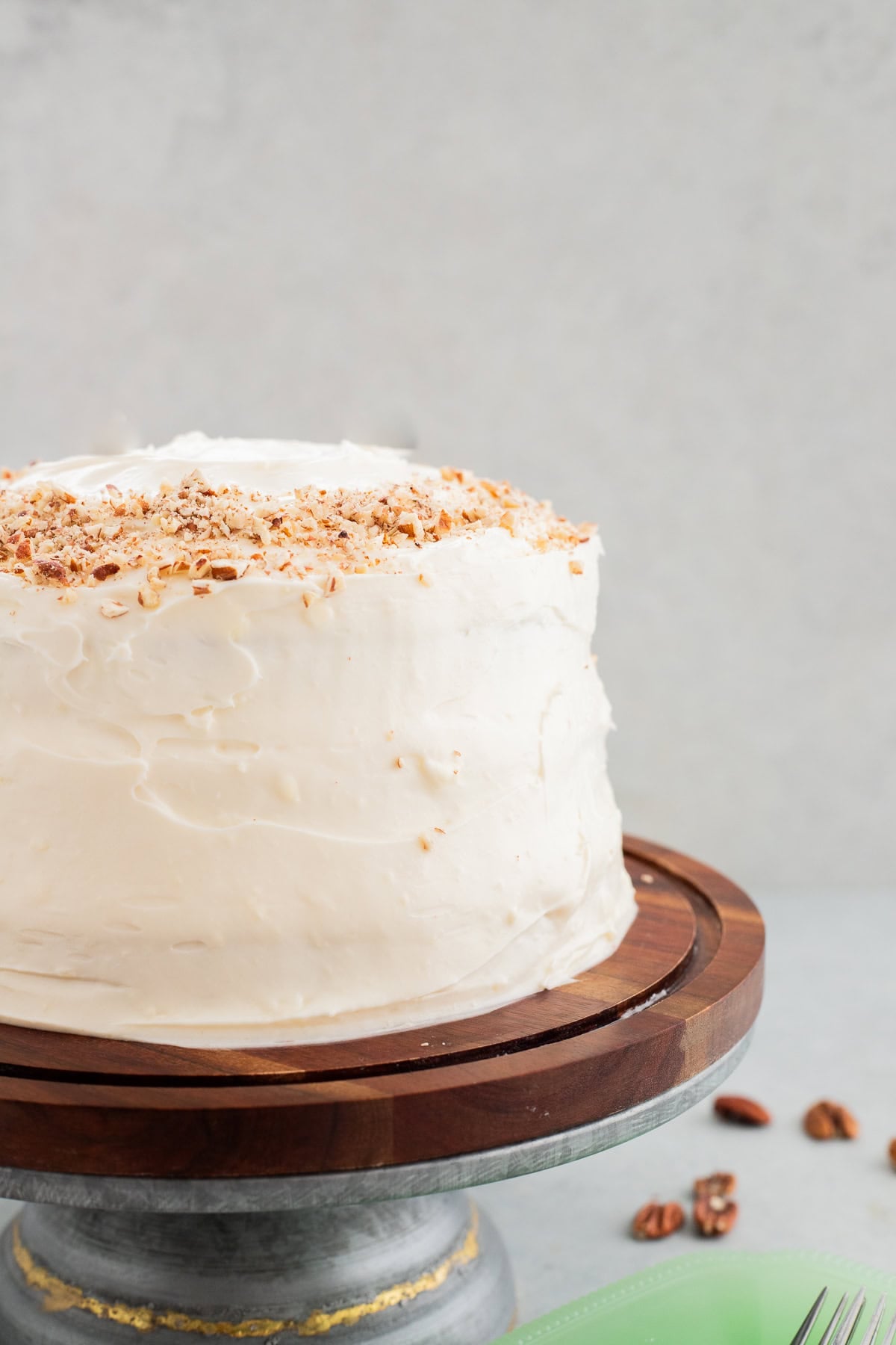 Frosted hummingbird cake on a wooden cake stand.