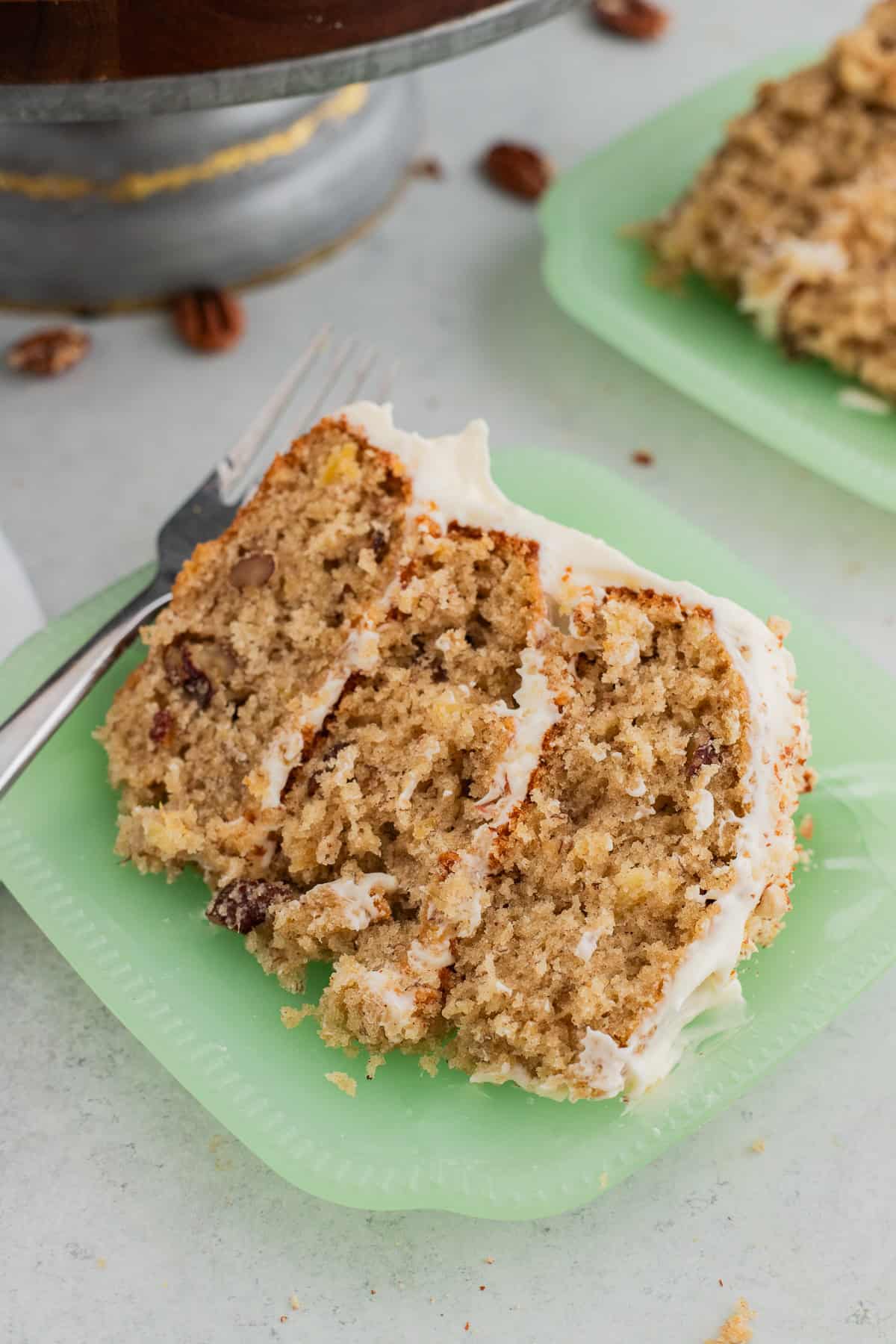 A slice of hummingbird cake on a green milk glass plate.