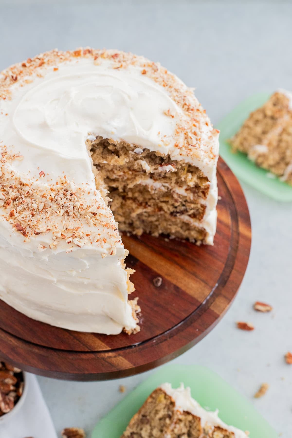 A humminbird cake with a slice taken out of it on a wooden cake stand.